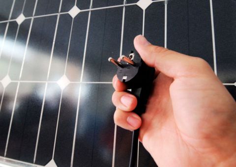 Balkonsolargerat und eine Hand mit einem Stromstecker