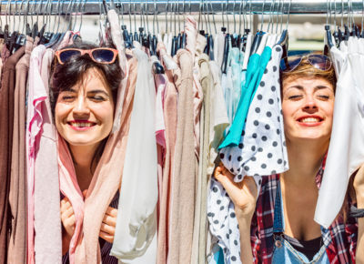 Zwei Frauen die Ihre Gesichter durch einen Kleiderständer stecken