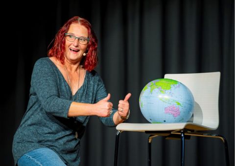 Anny Hartmann steht auf der Bühne zusammen mit einem Globus