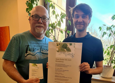Mitarbeiter der Stadt Bergkamen halten das Plakat für das 8. inklusive Salonmusikkonzert hoch