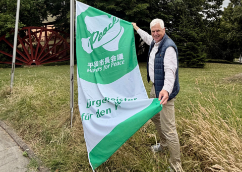 Thomas Heinzel hisst die Mayors for Peace Flagge