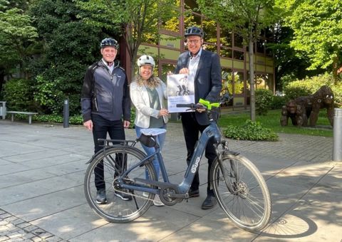 Bernd Schäfer und Carina Steffens stehen hinter einem Fahhrad und halten das AOK Plakat hoch