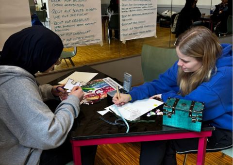 Zwei Jugendliche sitzen an einem Tisch