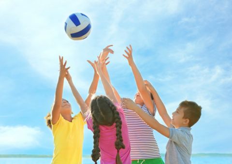 Vier Grundschulkinder spielen mit einem Ball