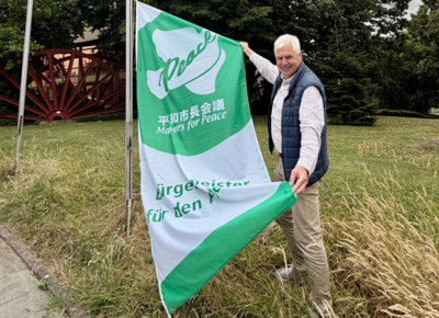 Thomas Heinzel hisst die Mayors for Peace Flagge